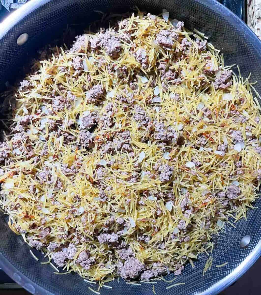 fideo, onions and ground beef cooking in a skillet