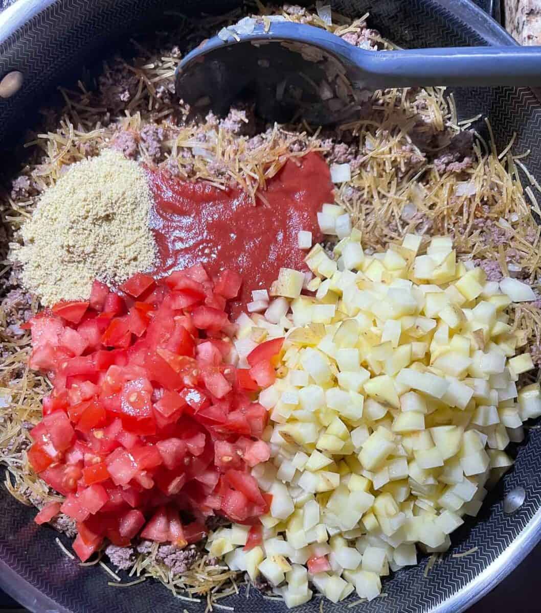 added tomatoes, tomato sauce, potatoes and chicken bouillon to the ground beef mixture
