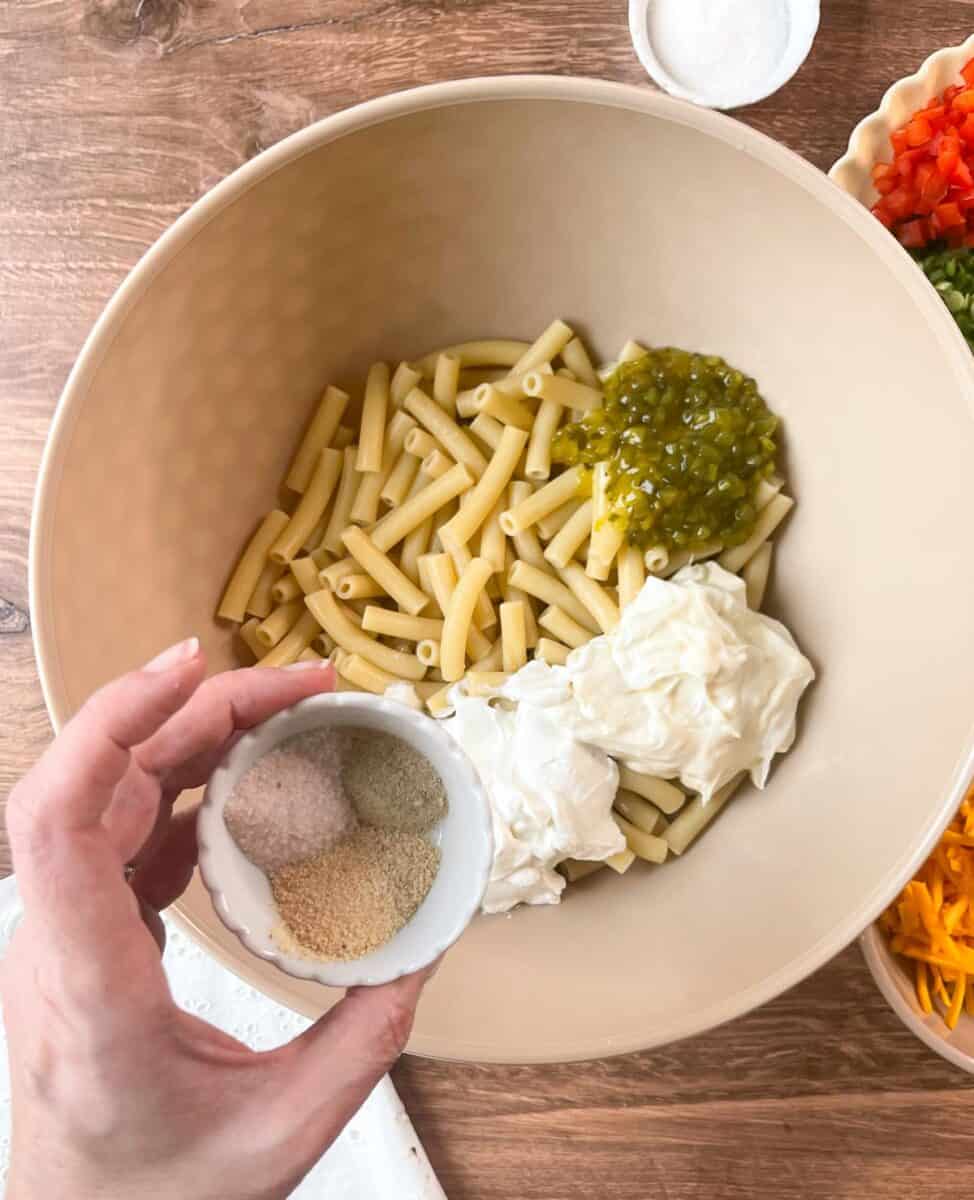 Adding seasonings to cooked macaroni in bowl