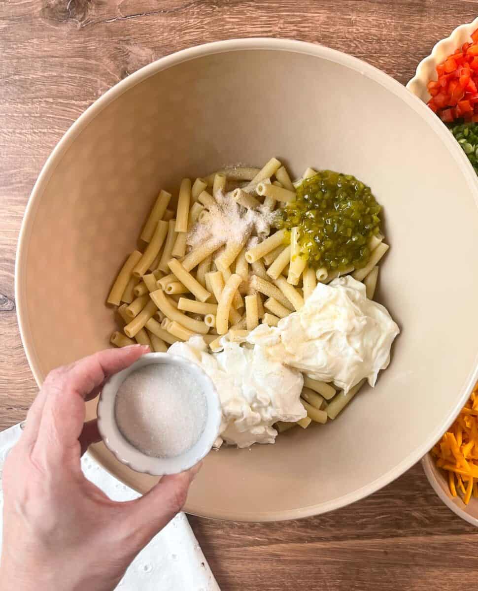 Adding sugar to cooked macaroni in bowl