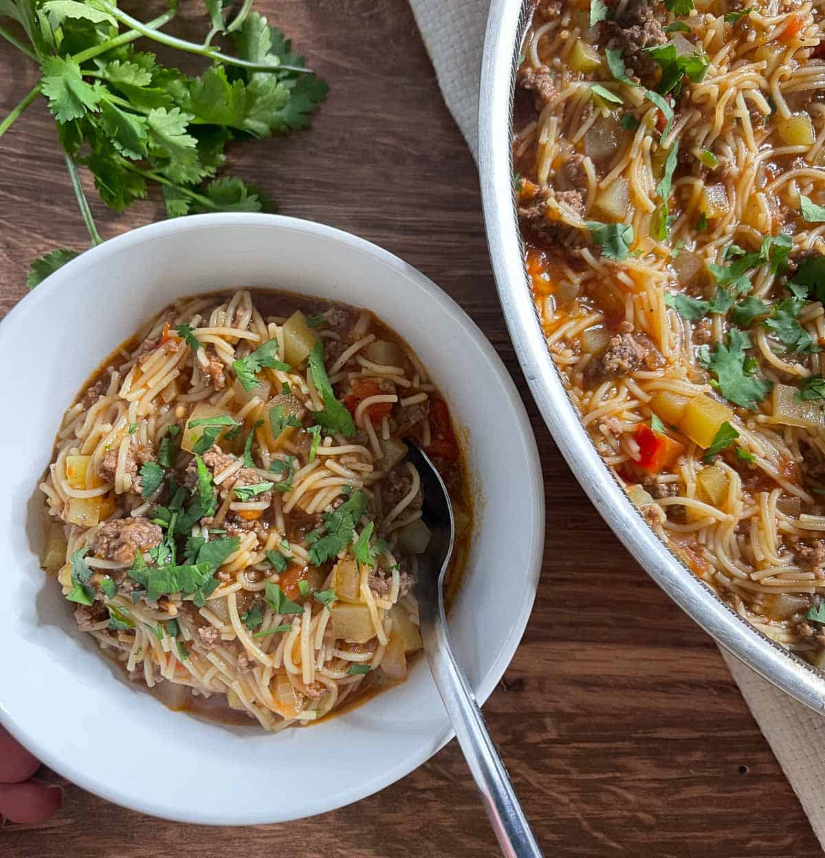 part of skillet showing of cooked fideo next to a small with bowl with a serving of the fideo in it